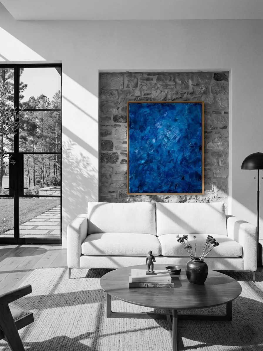 Blue Silence, a blue textured painting on a stone wall above a white sofa